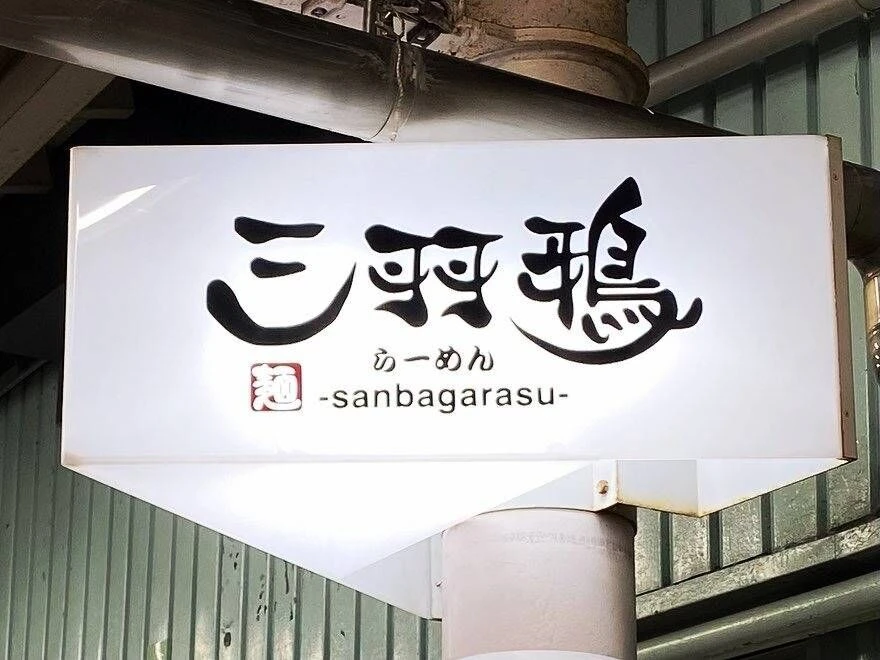 心機一転・三羽鴉の看板の文字はこの店舗より新たに変わります。住まう工房秦建築の代表と懇意にしている地元先輩の書で、全ての漢字の中にラーメン鉢をイメージした独特で印象に残る素敵な書です。
