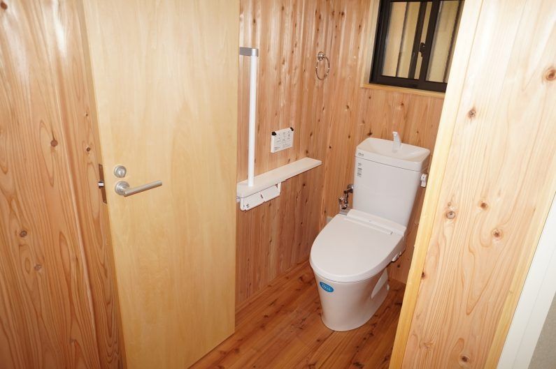 トイレは清潔感のある白色と杉板の温かい赤みのコントラストが最高ですね、扉は折れ戸を採用